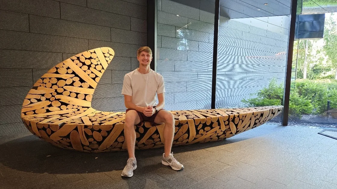 Sean seated on a wooden Nike swoosh bench